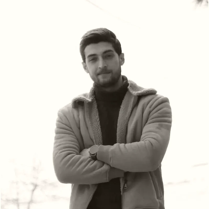 Ahmad Alawieh, arms folded, in a tan coat against an open sky