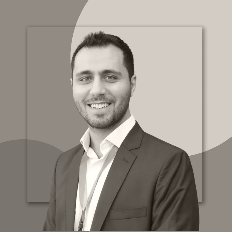 Majd Shams, in a navy suit and lanyard, smiling at the camera