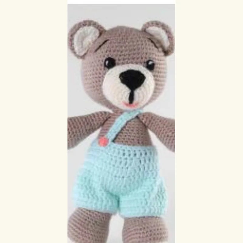 The same crocheted bear redesigned in blue dungarees, with cleaner finishing and brighter yarn