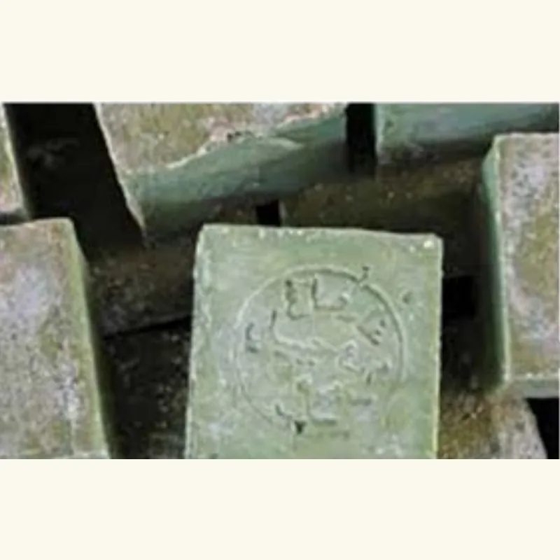 Rough unwrapped blocks of green Aleppo soap stacked on a workbench